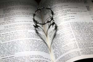 Crown of thorns on an open Bible, casting a shadow in the shape of a heart