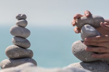 Hands stacking and balancing a stone tower, or cairn